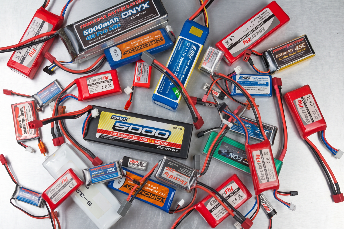 Why LiPo C-Ratings Are Overstated, and What to Check Instead Hand holding a LiPo battery with XT60 connectors next to a 5-inch FPV drone and spare packs on a backpack in a field