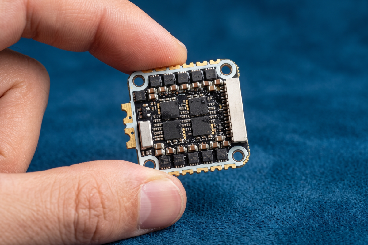 What Is an AIO Flight Controller? Compact FPV flight controller board held between two fingers to show its small size